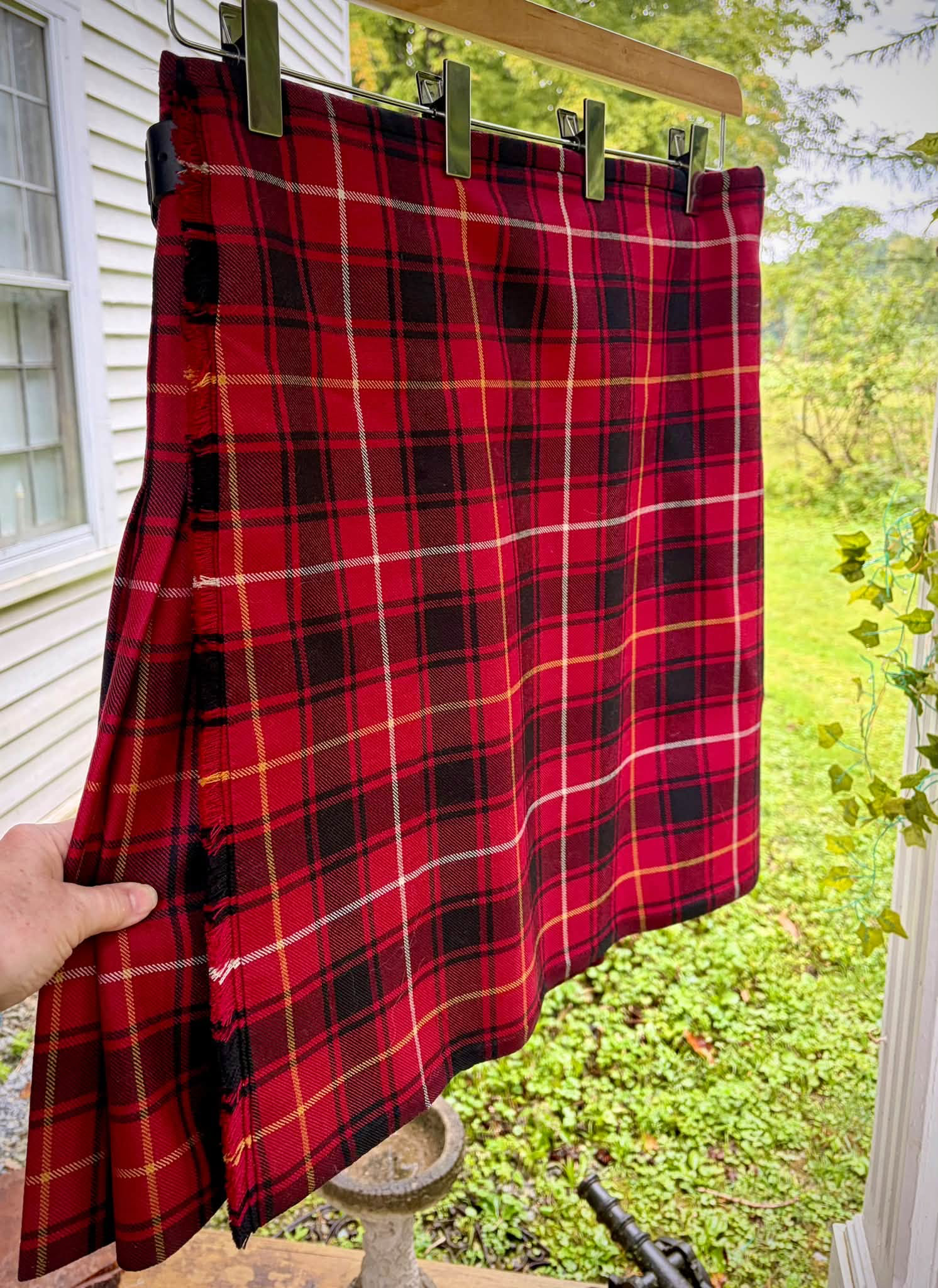 Red tartan kilt displayed outdoors.